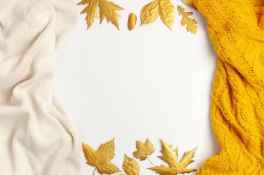Düz yatıyordu sonbahar kompozisyon. Örme yünlü açık bej ve sarı turuncu kazak veya ekose, beyaz arka plan üst görünüm kopya alanı altın kuru yaprakları. Sonbahar, sonbahar konsepti. Örme doku
