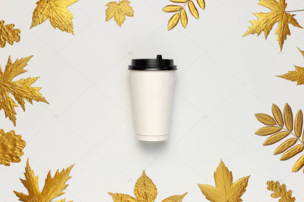 Coffee or tea paper cup, golden autumn leaves on light gray background top view flat lay. Take away coffee cup, mockup. Coffee love, layout for design. Fall concept. Autumn background. Copy space