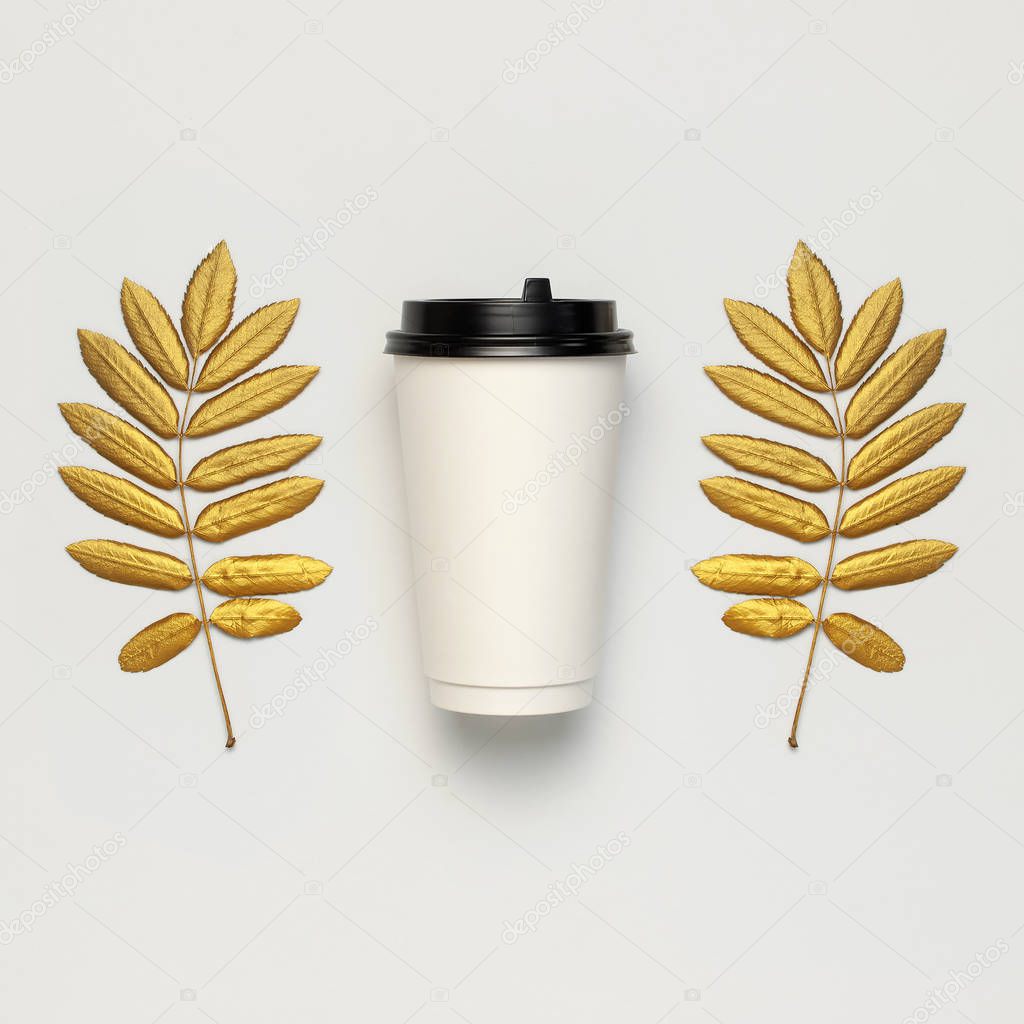 Coffee or tea paper cup, golden autumn leaves on light gray background top view flat lay. Take away coffee cup, mockup. Coffee love, layout for design. Fall concept. Autumn background. Square