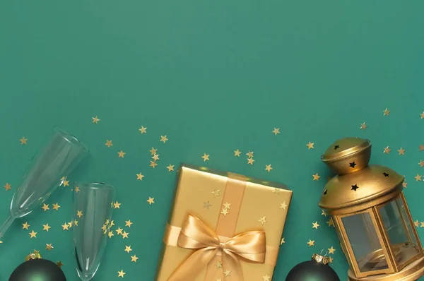 Neujahrsgeschenke, Weihnachtskugeln, Sektgläser, goldene Konfettisterne auf grünem Hintergrund von oben. Flach lag die Weihnachtsfeier 2020. Geschenk-Boxen Grußkarte festliche Dekoration — Stockfoto