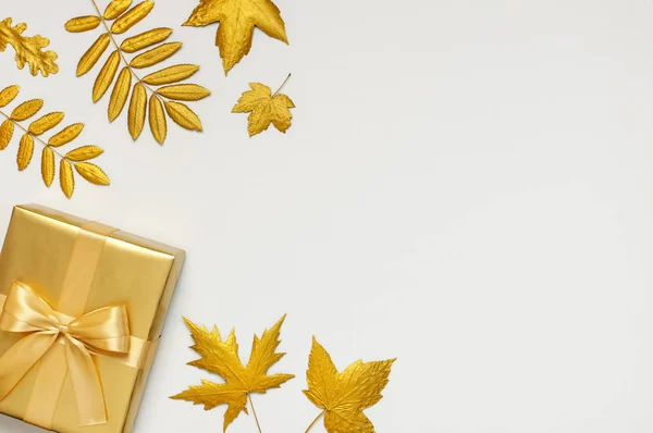 Flach lag das Herbstferienkonzept. goldenes Geschenk oder Geschenkkarton mit Schleife und goldenen Herbstblättern auf hellgrauem Hintergrund von oben kopieren Raum. Überraschung, Glückwunsch, Geburtstag, Grußkarte — Stockfoto