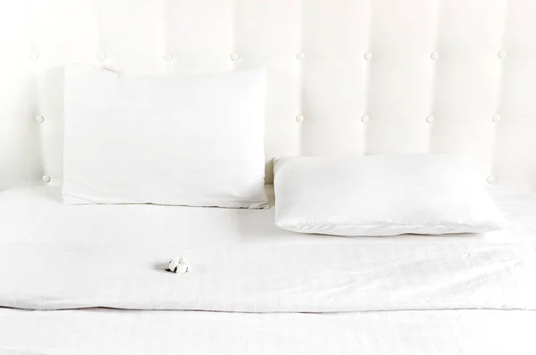 柔软的白色缝制枕头和棉花在床上，背景是白色皮革缝制床头板。干净的枕头，床特写的一部分，舒适。倾斜的床头板背景，床上用品模型 — 图库照片