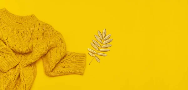 Autumn flat lay composition. Orange yellow knitted woolen female sweater and golden leaves on yellow background top view. Fashionable women\'s fall accessories. Cozy Knit Jumper Stylish Lady Clothes