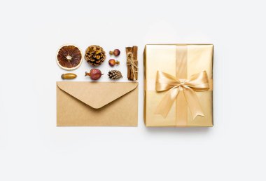 Düz yatıyordu Sonbahar tatil konsepti. Altın hediye veya kurdele, koni, tarçın, zarf, meşe palamudu, gri arka plan üst görünümünde kurutulmuş turuncu ile mevcut kutu. Sürpriz, tebrikler, doğum günü, tebrik kartı