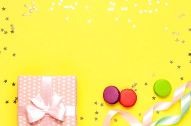 Hediye ya da hediye kutusu, güzel şenlik kurdelesi, pasta makaronu ya da badem kurabiyesi, sarı arka plan manzaralı konfeti. Kutlama, doğum günü, Sevgililer Günü, 8 Mart, Anneler Günü için beste.