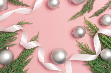 Gümüş Noel oyuncak topları, tatil kurdeleleri, pembe arka planda noel ağacı dalları. Düz görünüm kopyalama alanı yatıyordu. Yeni yıl kompozisyonu, kış dekorasyonu. En az kutlama konsepti