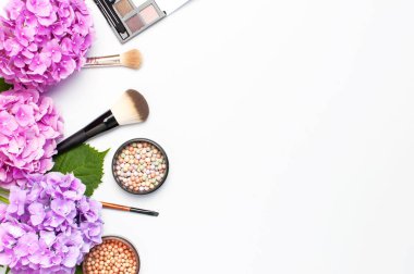 Dekoratif kozmetik maskara tozu ruj göz farı allık makyaj fırçası pembe ortanca çiçekler ışık arka plan üst görünümü Düz yatıyordu kopya alanı ayarlayın. Güzellik blogger kavramı. Moda arka plan