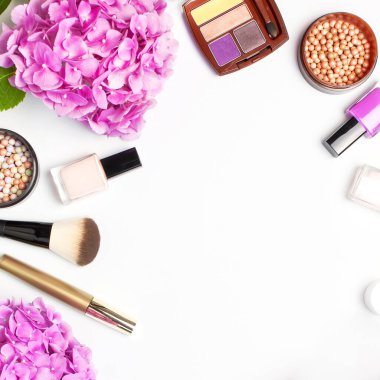 Dekoratif kozmetik maskara tozu ruj göz farı allık makyaj fırçası pembe ortanca çiçekler ışık arka plan üst görünümü Düz yatıyordu kopya alanı ayarlayın. Güzellik blogger kavramı. Moda arka plan