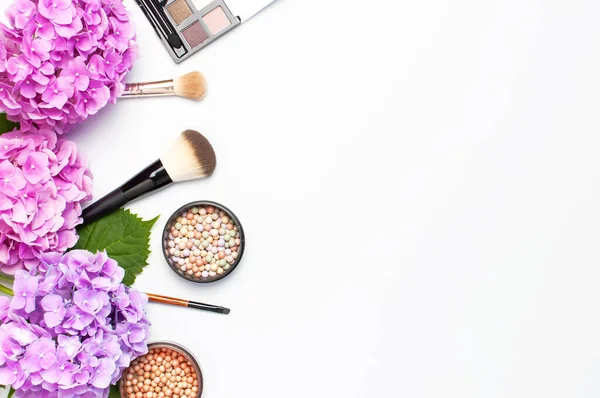 Dekoratif kozmetik maskara tozu ruj göz farı allık makyaj fırçası pembe ortanca çiçekler ışık arka plan üst görünümü Düz yatıyordu kopya alanı ayarlayın. Güzellik blogger kavramı. Moda arka plan