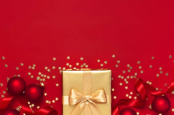 Piso laico fiesta de Navidad 2020 celebración. Navidad de Año Nuevo regalos de oro con cinta, bolas de Navidad, estrellas de confeti de oro sobre fondo rojo vista superior. Cajas de regalo tarjeta de felicitación Decoraciones festivas — Foto de Stock