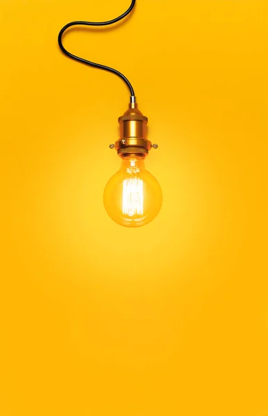 Vintage fashionable edison lamp on bright yellow background. Top view flat lay copy space. Creative idea concept, designer lamp, modern interior item. Lighting, electricity, background with lamp