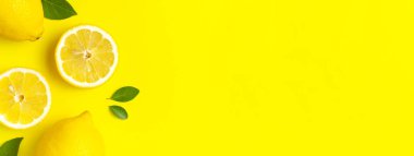Taze limonlar ve parlak sarı arka planda yeşil yapraklarla yaratıcı bir altyapı. Üst görünüm düz kopya alanı. Limonlu turunçgiller minimum C vitamini bileşimi, limon dilimleriyle.