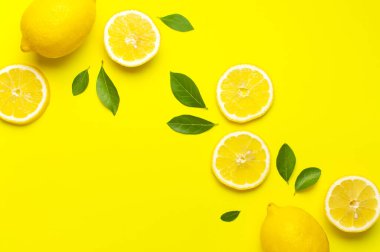 Taze limonlar ve parlak sarı arka planda yeşil yapraklarla yaratıcı bir altyapı. Üst görünüm düz kopya alanı. Limonlu turunçgiller minimum C vitamini bileşimi, limon dilimleriyle.
