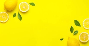 Taze limonlar ve parlak sarı arka planda yeşil yapraklarla yaratıcı bir altyapı. Üst görünüm düz kopya alanı. Limonlu turunçgiller minimum C vitamini bileşimi, limon dilimleriyle.