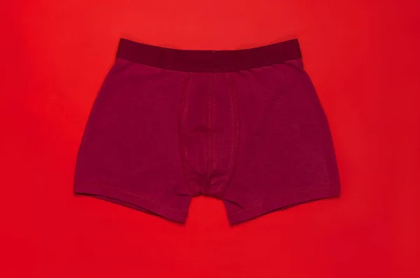 Men\'s underwear, red burgundy underpants on red background flat lay top view copy space. Fashion blog, natural underwear, advertising, shopping concept. Pants boxers