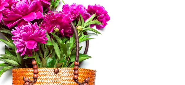 Bolso ecológico para mujer de paja o ratán de mimbre con hermosas flores de peonías rosadas sobre fondo blanco ver espacio de copia. Accesorio de moda femenina con peonías, concepto primavera verano, tarjeta con flores — Foto de Stock