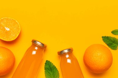 Yaratıcı yaz konsepti. Portakal suyu, taze tatlı portakallar, nane yaprakları ve sarı arka planda küvet içen cam şişeler. Sağlıklı yiyecekler, sağlıklı içecekler, C vitamini düz açılı fotokopi alanı..