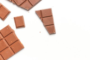 Beyaz arka planda fındıklı sütlü çikolata parçaları üst manzara fotokopi alanında yatıyordu. Minimalist Çikolata Arkaplanı. Çikolatalı kakao, şeker, aşırı kilolu çikolata bağımlılığı..