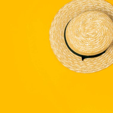 Sarı arka planda kadınların hasır şapkası düz bir şekilde duruyor. Yaz tatili konsepti, tek parça. Kadın aksesuar, yaz geçmişi. Deniz güneşi tatil plajı.
