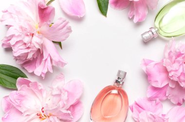 Parfüm ve çiçeklerle güzel bir kompozisyon. Parfüm şişesi, pembe çiçekler şakayık yeşil yapraklar açık arkaplanda düz zemin üzerinde fotokopi alanı uzanıyor parfüm kozmetik tuvalet suyu koku koleksiyonu.