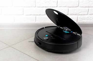 Ev Temizliği Konsepti. Modern robot elektrikli süpürge, tuğla duvara karşı porselen fayanslardaki evleri temizliyor. Yeni teknolojiler, hızlı ev temizleme otomatik robot asistanı. Temizlik için akıllı aygıt.