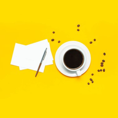 Bir fincan sade kahve, kahve çekirdekleri, siyah alarm saati, kalemler, sarı zemin üzerinde beyaz kağıt kağıtlar düz açılı fotokopi alanı yatıyordu. Yaratıcı kavram çalışma zamanı, kadın masaüstü, kahve arkaplanı.