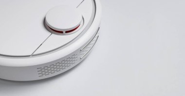 Gri arka planda modern robot elektrikli süpürge yatıyordu. Yeni teknolojiler, hızlı ev temizliği, otomatik robot asistanı. Rahatlamak için boş zaman. Gelecek teknolojisi, temizlik için akıllı aygıt.
