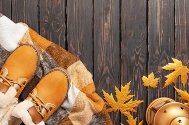 Sonbahar Moda Konsepti. Kahverengi turuncu deri kadın botları kürklü, ekoseli, kahverengi ahşap arka plan manzaralı altın sonbahar yaprağı. Modaya uygun kadın ayakkabıları. Samimi sonbahar kompozisyonu