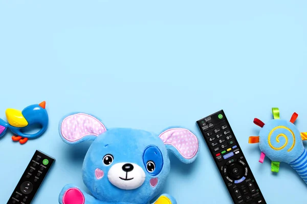 Siyah TV ses uzaktan kumandası ve bebek oyuncakları, mavi arka planda oyuncak köpek yavrusu düz görünüm fotokopi alanı yatıyordu. Çocuk televizyon programlarını, çizgi filmleri, çocuk filmlerini izleme kavramı. Ev eğlencesi..