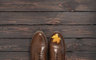 Kahverengi deri erkek ayakkabıları ve koyu ahşap arka plan manzaralı sonbahar altın yaprakları. Sonbahar Moda Konsepti. Modaya uygun erkek ayakkabıları. Samimi sonbahar kompozisyonu. İndirim, ayakkabı reklamı..