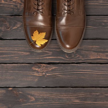 Kahverengi deri erkek ayakkabıları ve koyu ahşap arka plan manzaralı sonbahar altın yaprakları. Sonbahar Moda Konsepti. Modaya uygun erkek ayakkabıları. Samimi sonbahar kompozisyonu. İndirim, ayakkabı reklamı..