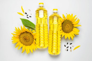 Ayçiçeği yağlı plastik şişeler, taze sarı ayçiçekleri, gri arka planda ayçekirdeği. Düz görünüm kopyalama alanı yatıyordu. Hasat zamanı tarım petrol üretimi. Sağlıklı yağlar, yiyecek..