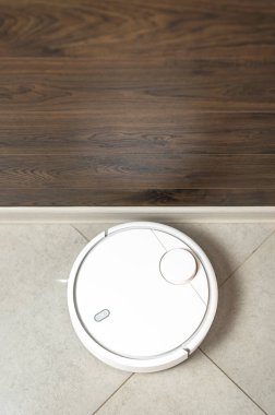 Ev Temizliği Konsepti. Modern robot elektrikli süpürge koridordaki porselen taş kaplama döşemeyi temizliyor. Yeni teknolojiler, hızlı ev temizleme otomatik robot asistanı. Temizlik için akıllı aygıt.