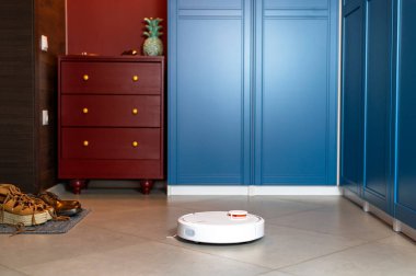 Ev Temizliği Konsepti. Modern robot elektrikli süpürge koridordaki porselen taş kaplama döşemeyi temizliyor. Yeni teknolojiler, hızlı ev temizleme otomatik robot asistanı. Temizlik için akıllı aygıt.