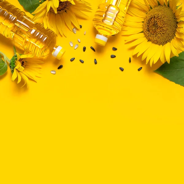 Bottiglie di plastica con olio di girasole, girasoli gialli freschi, semi di girasole su fondo giallo. Flat lay vista dall'alto spazio copia. Tempo di raccolta agricoltura produzione di olio. Oli sani, cibo — Foto Stock