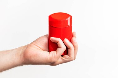 Erkeklerin elindeki kırmızı deodorant beyaz arka planda izole edilmiş. Erkek deodorantı, kişisel hijyen ürünleri, erkek kozmetiği. Kırmızı temiz plastik deodorant ambalajı, reklam için model, metin için yer.