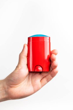 Erkeklerin elindeki kırmızı deodorant beyaz arka planda izole edilmiş. Erkek deodorantı, kişisel hijyen ürünleri, erkek kozmetiği. Kırmızı temiz plastik deodorant ambalajı, reklam için model, metin için yer.
