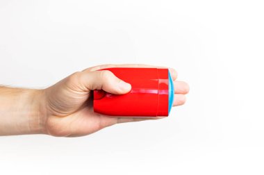 Erkeklerin elindeki kırmızı deodorant beyaz arka planda izole edilmiş. Erkek deodorantı, kişisel hijyen ürünleri, erkek kozmetiği. Kırmızı temiz plastik deodorant ambalajı, reklam için model, metin için yer.