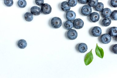 Yabanmersini arka planı. Beyaz arka planda yeşil yapraklı taze, sulu yabanmersini. Düz görünüm kopyalama alanı yatıyordu. Sağlıklı böğürtlen, organik gıda, antioksidan, vitamin, mavi gıda. Yabanmersini çerçevesi.