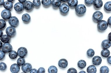 Yabanmersini arka planı. Beyaz arka planda yeşil yapraklı taze, sulu yabanmersini. Düz görünüm kopyalama alanı yatıyordu. Sağlıklı böğürtlen, organik gıda, antioksidan, vitamin, mavi gıda. Yabanmersini çerçevesi.