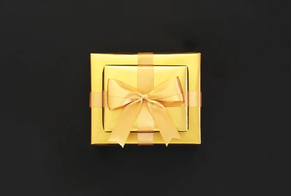 黒の背景にリボン付きの黄金の贈り物 フラットレイアウト トップビュー コピースペース 黄金の装飾 パーティー 誕生日 休日のコンセプト ギフトボックス お正月やクリスマスの構図 — ストック写真