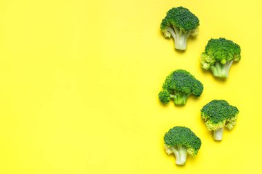 Yaratıcı gıda konsepti. Sarı arka planda taze çiğ yeşil brokoli. Sağlıklı sebzeler, diyet organik yiyecekler, vitaminler. Düz görünüm kopyalama alanı yatıyordu. Brokoli lahanası soyut desen.