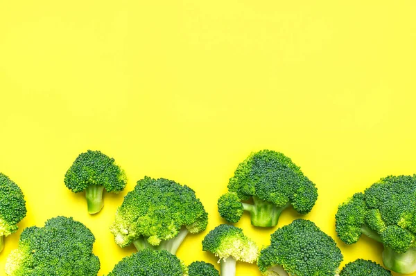 Creative food concept. Fresh raw green broccoli on yellow background. Healthy vegetables, diet vegan organic food, vitamins. Flat lay top view copy space. Broccoli cabbage abstract pattern.