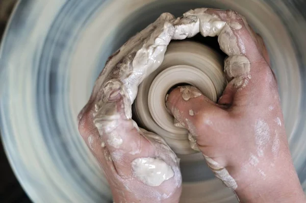 Pottery training. The hands of the pupil and master over the potter\'s wheel.
