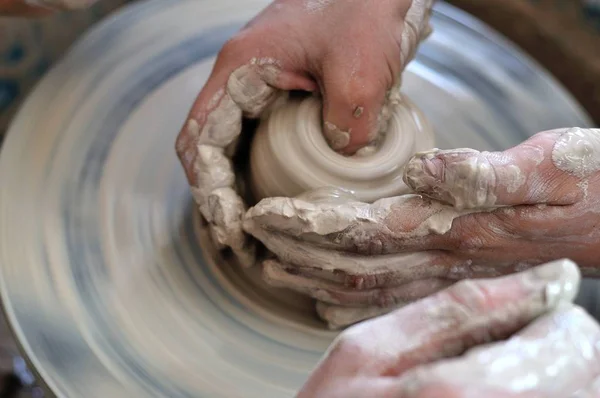 Pottery training. The hands of the pupil and master over the potter's wheel.