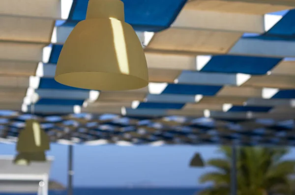 Protective cloth white-blue sunshade with illumination. The roof of the beach bar in the hotel. The coast resorts of the Aegean Sea of Turkey. Turgutreis , Bodrum.