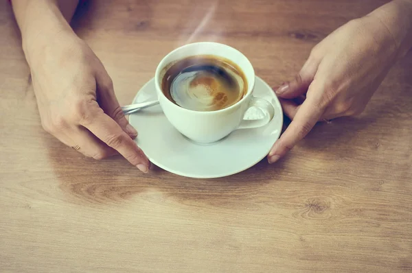 Closeup hand with a cup of cappuccino coffee. Color toning in retro style. Lifestyle person at the weekend.