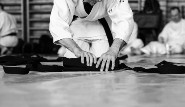Black and white image of aikido. The male athlete carefully folds the black hackam. The traditional form of clothing in Aikido.