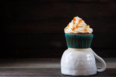 Karanlık bir arka plan üzerinde krem karamel ile cupcakes
