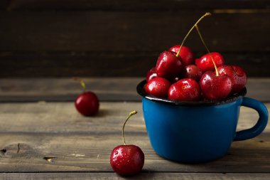 Bir mavi Mine kupa koyu ahşap arka plan üzerinde güzel damla taze kiraz